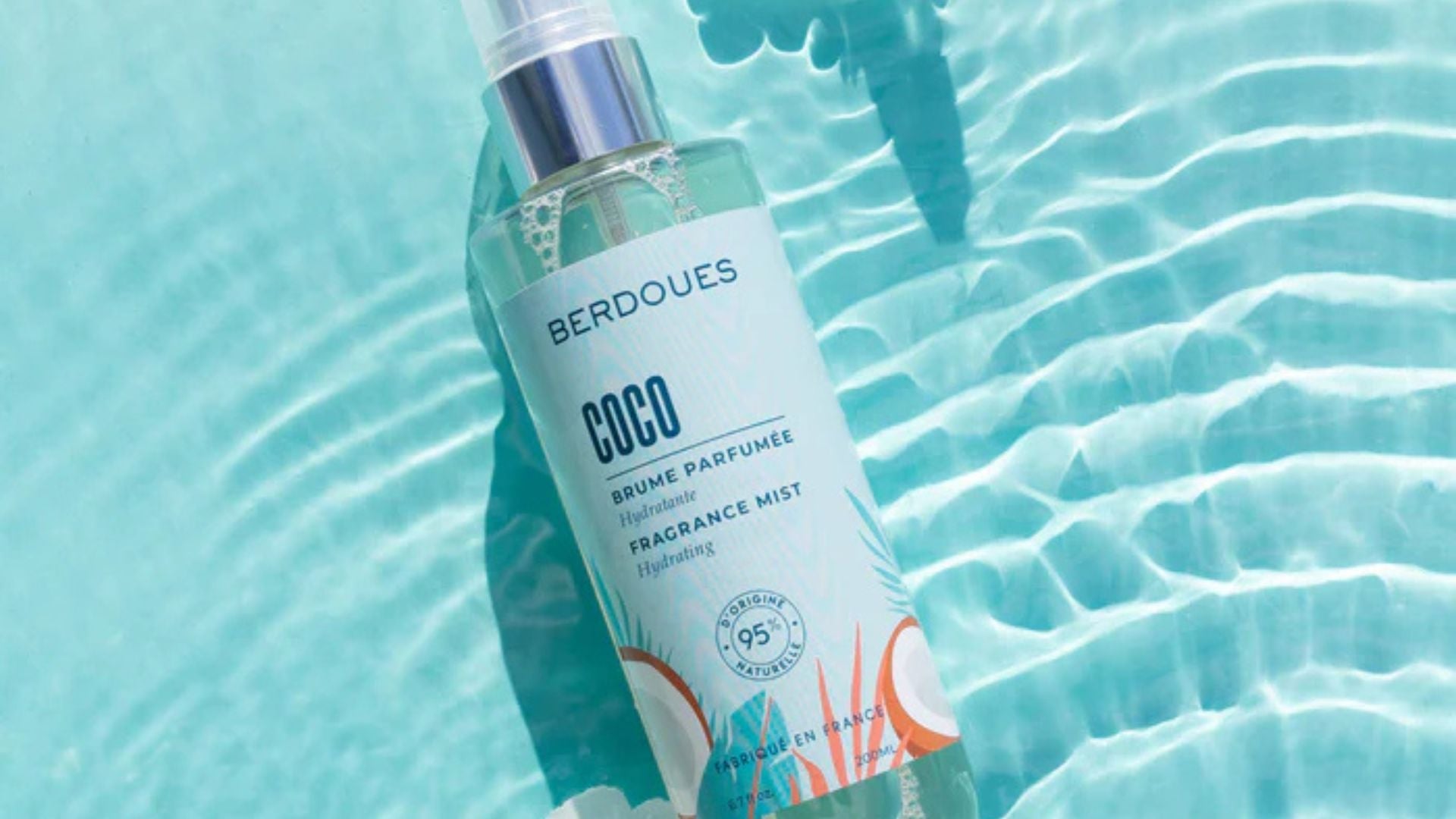 Brume parfumée hydratante Coco de Berdoues flottant à la surface d’une eau turquoise, illustrant fraîcheur et légèreté estivale.