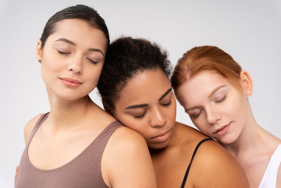 Trois femmes aux carnations différentes posant côte à côte, illustrant la diversité des peaux et leur influence sur la perception du parfum.