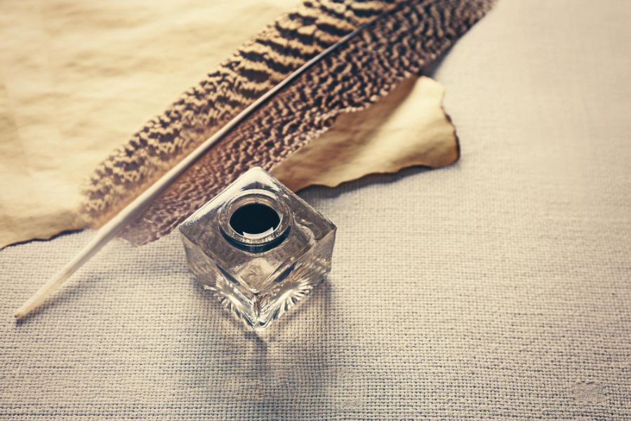 Flacon de parfum posé sur un tissu naturel avec plume illustrant la recherche d’un parfum signature personnel et élégant
